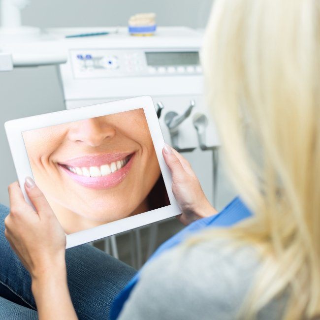 Woman looking at facial simulation of digital smile design on tablet computer