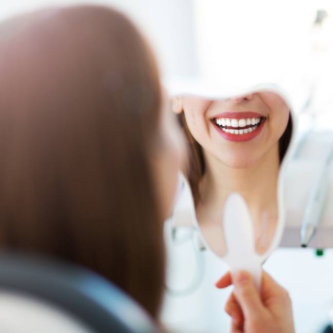 Woman looking at her smile after cosmetic oral surgery