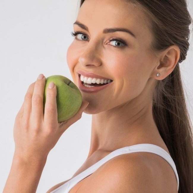 Woman eating an apple after dental implant tooth replacement