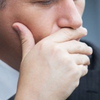 Man missing all teeth covering his mouth