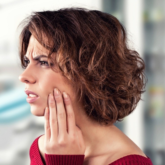 Woman with soft tissue facial injury holding her cheek