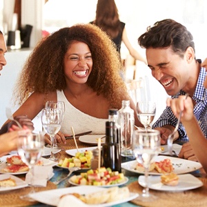 Friends enjoying meal together, enjoying benefits of dental implants