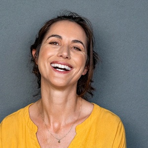 Smiling woman enjoying money-saving benefits of dental implants