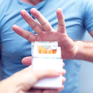 Man declining offer of cigarette after his dental implant surgery