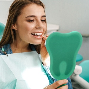 Happy patient admiring her new dental implant restorations