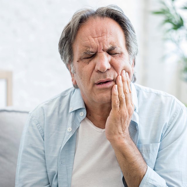 Man with mouth pain sitting on sofa