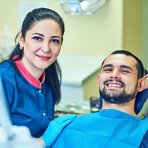 Dental team member next to relaxed, happy patient