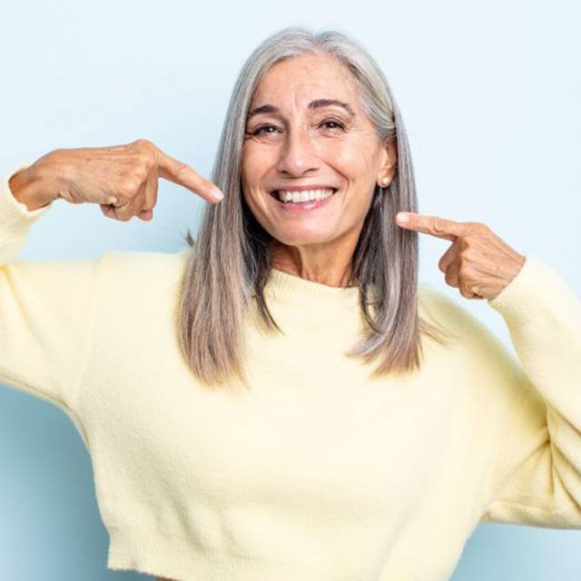 Smiling senior woman pointing at her teeth
