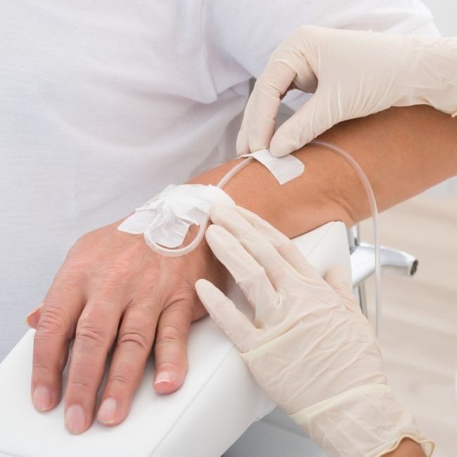 Team member placing needle for intravenous anesthesia and dental sedation