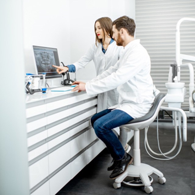 Dental team members conversing in front of computer