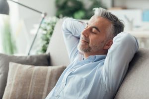 Man relaxing on sofa after All-on-4 surgery