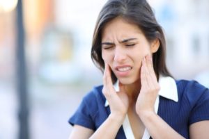 Woman with jaw pain, experiencing symptoms of untreated TMD