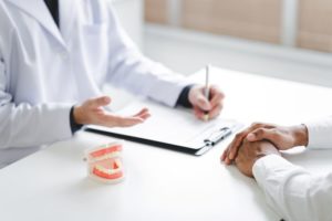 Oral surgeon and patient sitting at desk during consultation