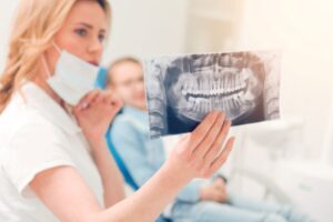 Dental team member examining patient’s X-ray