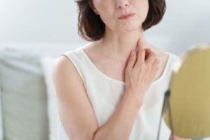 Mature woman looking at her neck in mirror 