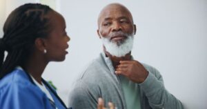 Concerned man touching his throat, speaking to healthcare professional
