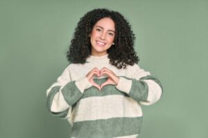 Smiling woman making a heart shape with her hands 