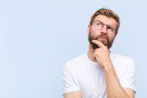 Man wearing thoughtful expression, standing against blue background