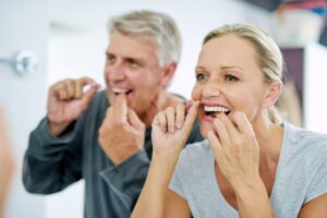 Middle-aged couple flossing in bathroom 